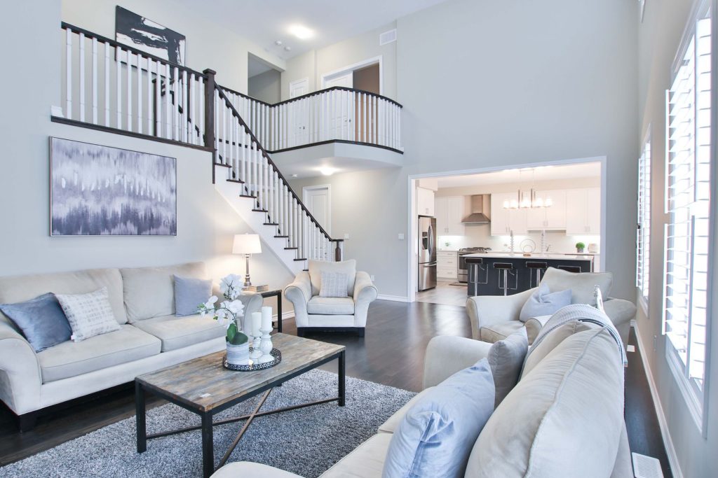 White furniture set and coffee table, stairs, and the kitchen behind them
