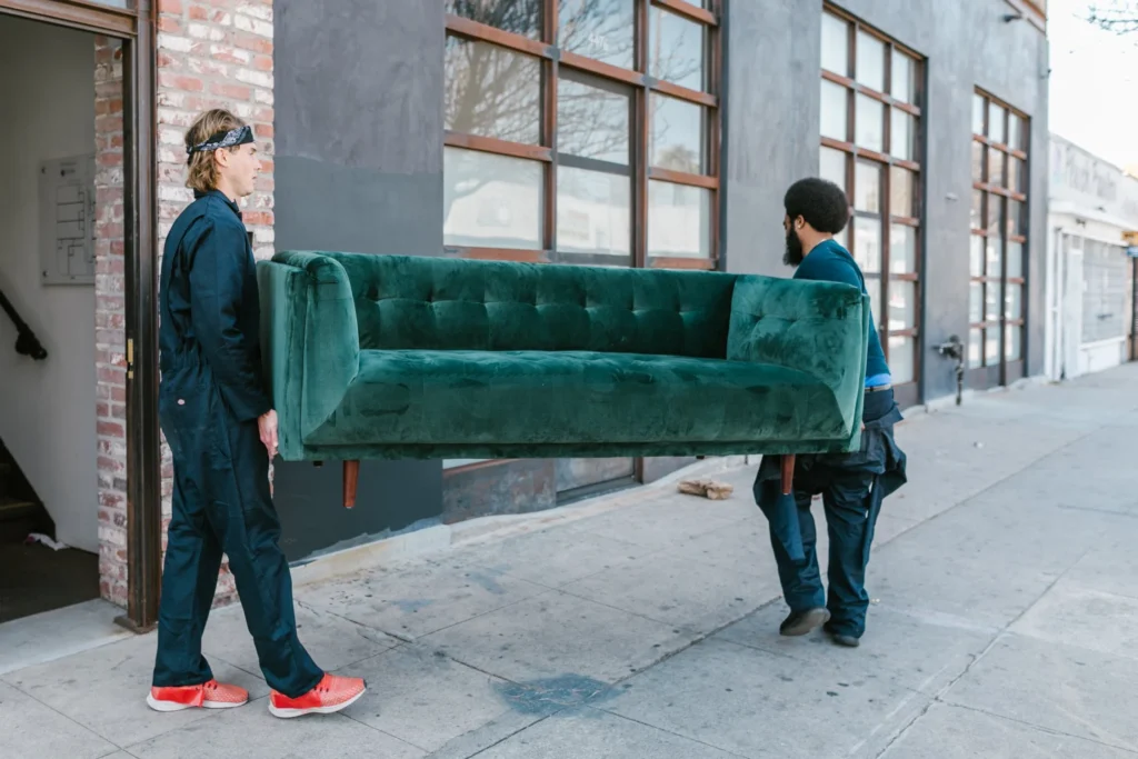 mover carrying a heavy green couch